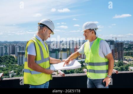 Male engineers reading blueprint together Stock Photo