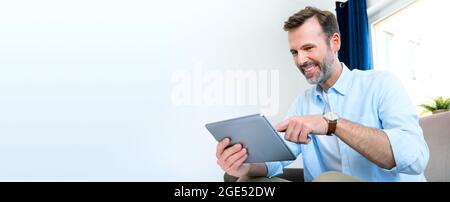 Handsome businessman working from home. Using app on tablet to telecommuting or sales reporting Stock Photo