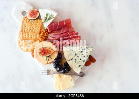 Appetizer platter with assorted cheeses and cold cut meats. Top view on a white marble background. Stock Photo