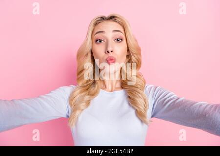Photo of charming young happy woman send air kiss you make selfie isolated on pastel pink color background Stock Photo