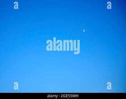 detail of the moon in crescent phase in the northern hemisphere over blue sky Stock Photo
