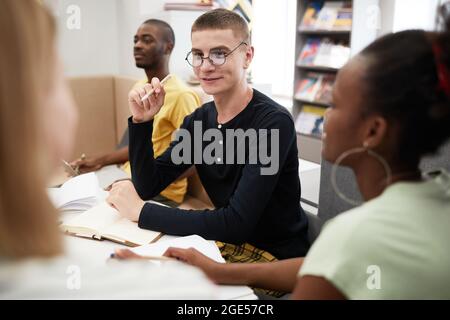 Portrait of smiling young man studying with group of friends in college library Stock Photo