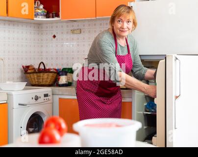 Elderly woman cooks preparing food in the kitchen Stock Photo