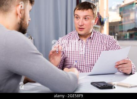 Two serious men analysing documents at table Stock Photo