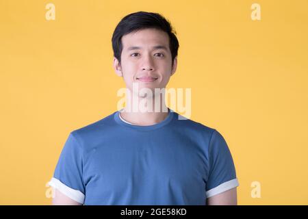 Close up portrait of smiling handsome Asian young man isolated on yellow background Stock Photo