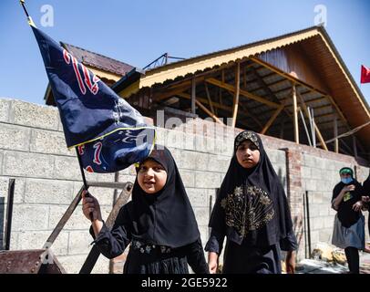 A Kashmiri Shia girl hold a religious flag during a muharram procession ...