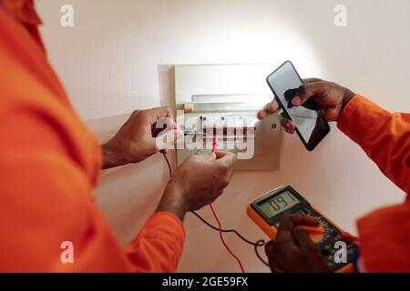 Hands of technicians using multimeter when testing electric current in Watt hour meter Stock Photo