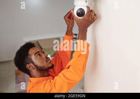 Technician in orange uniform installing video surveillance in office building Stock Photo