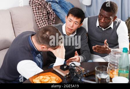 Friends soothing upset man Stock Photo