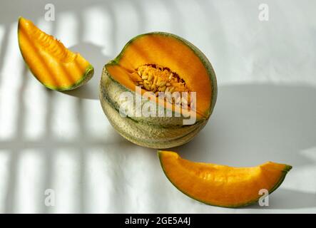 Whole and sliced Japanese melon, cantaloupe melon on white background under the sunshine in front of the window Stock Photo