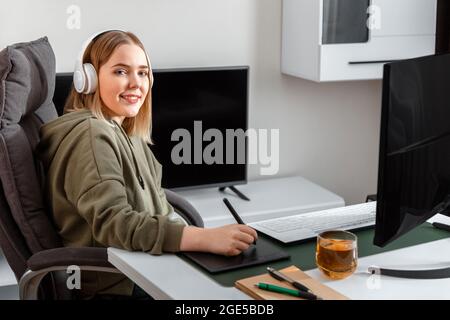 Portrait of Young artist graphic designer. Caucasian blonde woman drawing on graphic tablet by Stylus pen using pc monitor at home office interior Stock Photo