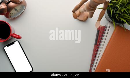 Flat lay composition with copy space on light grey background surrounded by smartphone mockup, red coffee mug, books, figure, alarm clock, plant Stock Photo