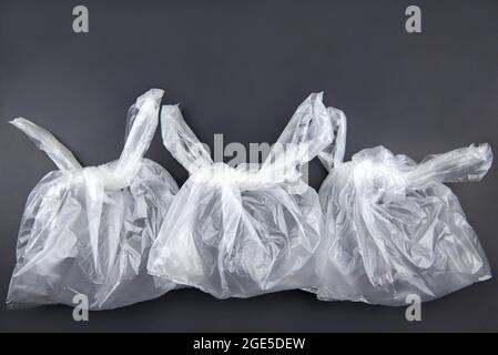 Three plastic bags on dark background, environmental pollution concept. Stock Photo
