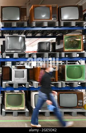 Heusenstamm, Germany. 10th Aug, 2021. Tina Kubot, Conservator of Media History, walks past a high rack of television sets in the Museum of Communication - Collections (slow shutter speed shot). On 22 August 1931, the first electronic television set was demonstrated at a technology show in Berlin. (to dpa 'The mother of all gawkers: Electronic television has 90th birthday'') Credit: Arne Dedert/dpa/Alamy Live News Stock Photo