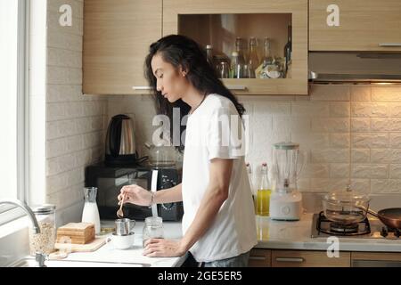 Handsome young man in white shirt standing at kitchen counter and making Vietnamese style coffee in the morning Stock Photo
