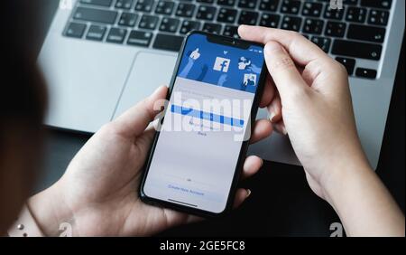 CHIANG MAI ,THAILAND - APR 10, 2021 : Woman hand holding iPhone 6S to use facebook with new login screen.Facebook is a largest social network and most Stock Photo