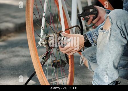 Close-up image of man checking bicycle chain and fixing pedals Stock Photo
