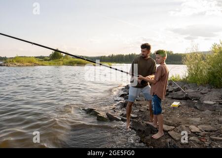 Premium Photo  Contemporary teenage boy with long rod fishing alone by lake