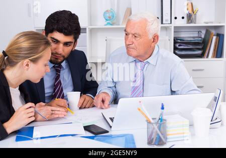 Office workers are writing financial reports and discussing with mature boss Stock Photo