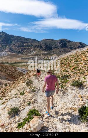 Three tourists hiking in a volcanic caldera with pumice fields, yellow coloured sulphur stones, Alexandros crater, Nisyros, Dodecanese, Greece Stock Photo