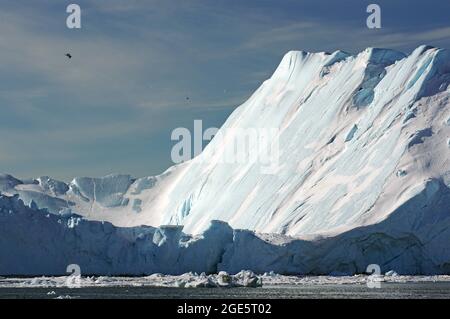 Small fishing boat in front of huge icebergs and drift ice, seagulls, winter, Disko Bay, Ilulissat, West Greenland, Denmark Stock Photo