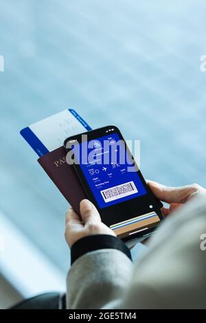 Passenger holding smartphone checking travel information on electronic boarding pass before flying. traveler using digital boarding pass for air trave Stock Photo