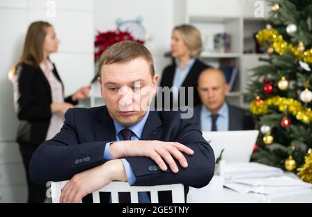 Business team tensely solving problems in office with offended man foreground Stock Photo