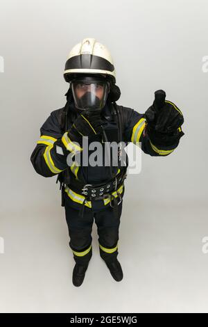 One male firefighter dressed in uniform posing over white studio background. Stock Photo