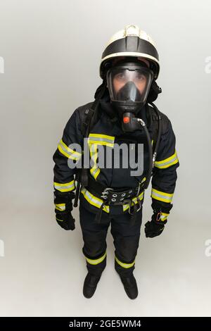 One male firefighter dressed in uniform posing over white studio background. Stock Photo