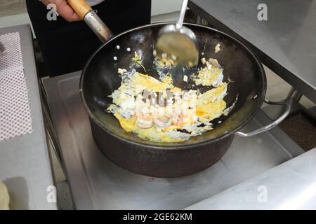 High angle view of stir fry food. Egg, shrimp and pieces of tofu being cooking in black iron wok. Stock Photo