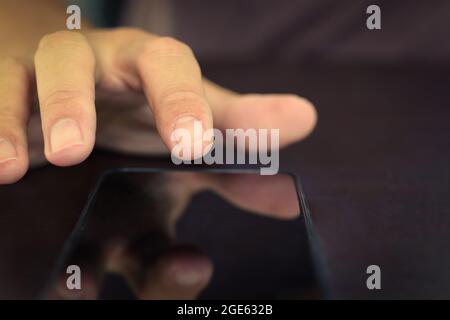 Close up of hand finger pointing on a device mobile phone. Stock Photo