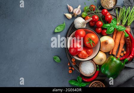 Fresh vegetables, spices, ingredients for making tomato sauce on a gray-blue background. Stock Photo