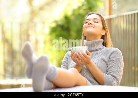 Carefree woman breathing fresh air relaxing drinking coffee in a garden at home in winter Stock Photo