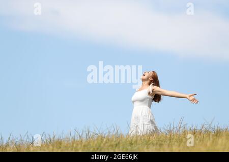 Excited woman screaming to the air outstretching arms in a wheat field Stock Photo