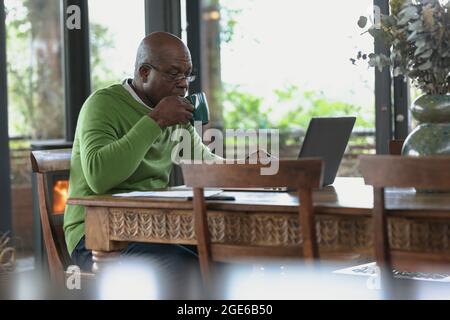 Senior african american man siting and working on laptop in the modern living room Stock Photo