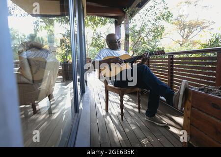 Senior african american man on sunny balcony playing the guitar Stock Photo
