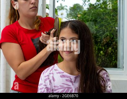 mom combing her daughter's hair in the bedroom Stock Photo