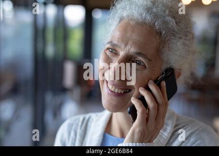 Happy senior caucasian woman standing and using smartphone Stock Photo
