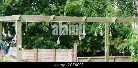 Some outdoor light bulbs hanging from a garden shelter Stock Photo