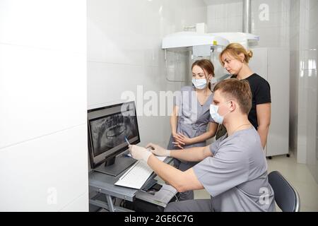 A team of young dentists works in a well-equipped office. Dentists take a picture of the patient's jaws Stock Photo