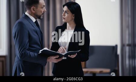 Business partners discussing documents while standing in lobby of restaurant,stock image Stock Photo