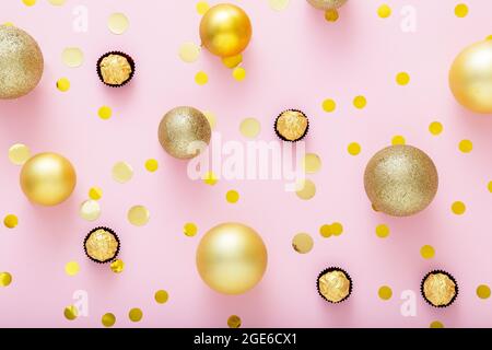 Pink festive Christmas background with Golden christmas decorations with sweets Candies Golden confetti on pink color background. Background texture Stock Photo