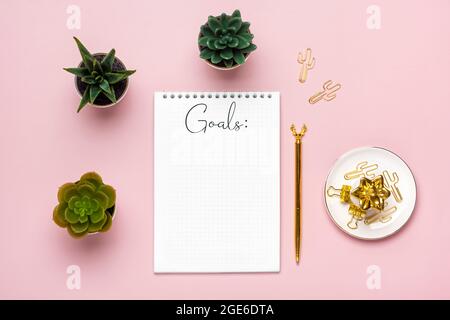 open notepad with text Goals 2022 goals, succulents, golden pen on pink background, spiral notebook on table Business, planning, education concept Stock Photo