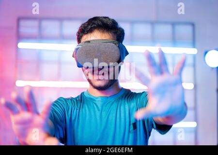 Amazed Young man first time experiencing vr or virtual reality headset on neon light background - concept of futuristic and modern technology. Stock Photo