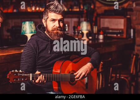 Bearded guitarist plays. Bearded man playing guitar, holding an acoustic guitar in his hands. Play the guitar. Music concept Stock Photo