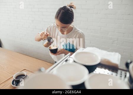 Nice female barista making latte art in cafeteria Stock Photo