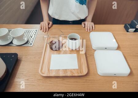 Female barista standing behind counter in coffee shop Stock Photo