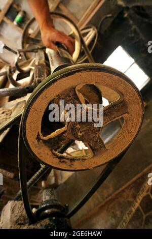 Old, dusty and rusty cast iron wheel of rice mill machine. Photo taken in a rice milling plant in Benguet, Philippines on October 1, 2019. Stock Photo
