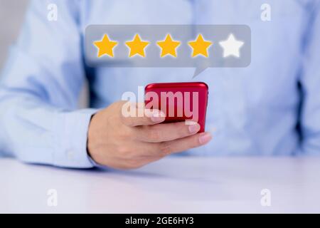 Customer holding phone and pressing star icon for vote score review and feedback with quality and satisfaction, success of digital marketing with resu Stock Photo