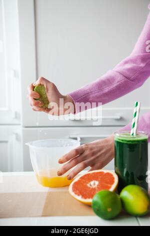 Closeup photo of a woman squeezing lemon juice in kitchen. Squeeze lemon juice in kitchen. Fruit juice. Dieting and health eating concept. Stock Photo